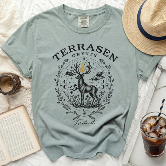 Sage green t-shirt featuring a black and gold graphic of a stag surrounded by botanical and celestial motifs.