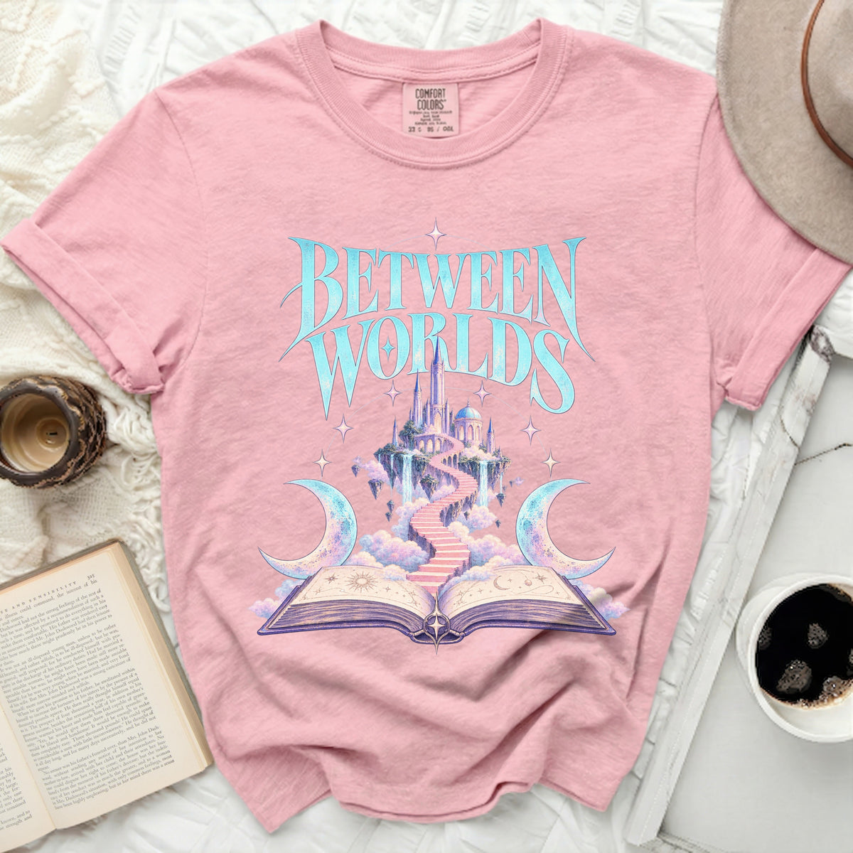 Pink t-shirt with "Between Worlds" text and celestial castle design.
