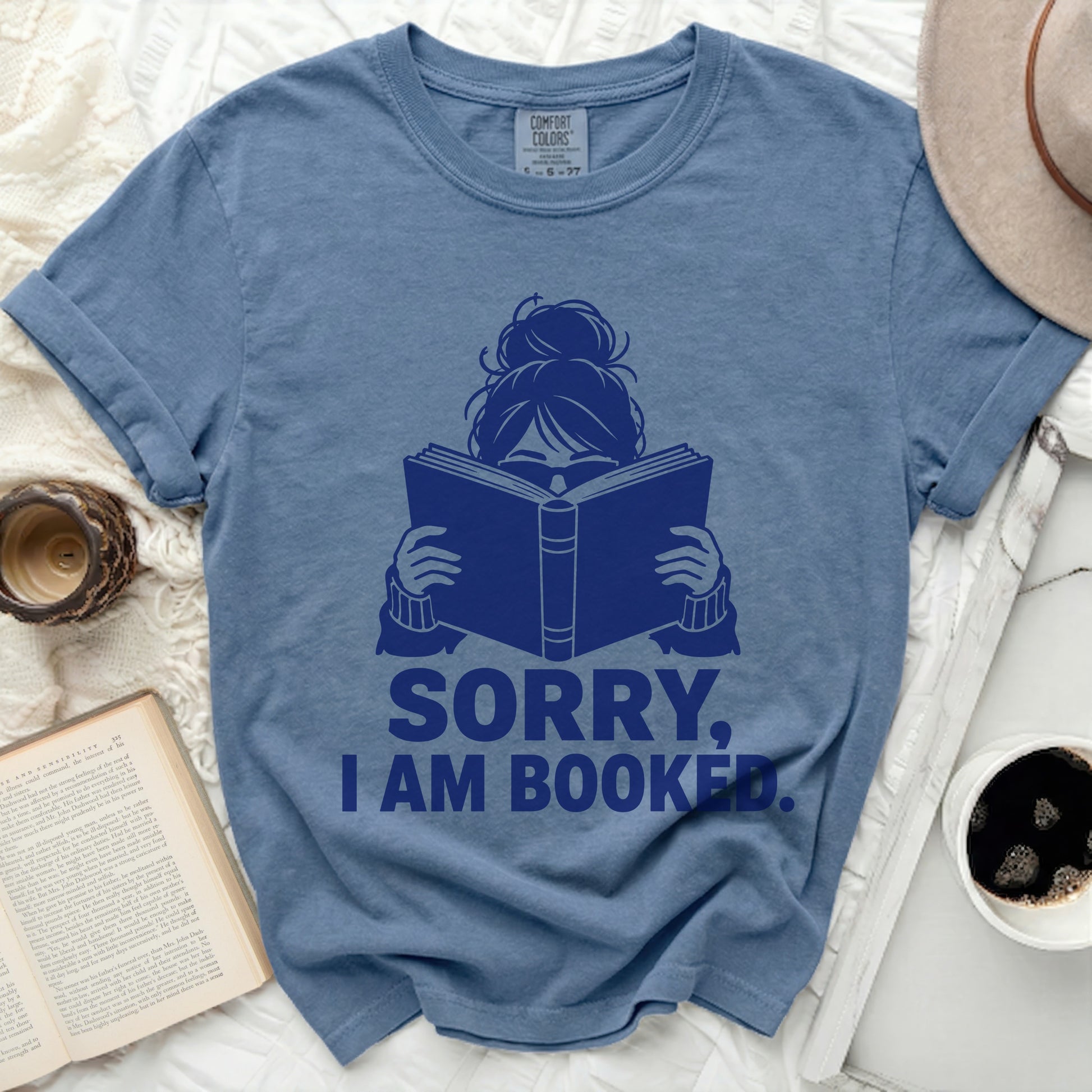 Blue t-shirt with "SORRY, I AM BOOKED." text and a graphic of a person reading.