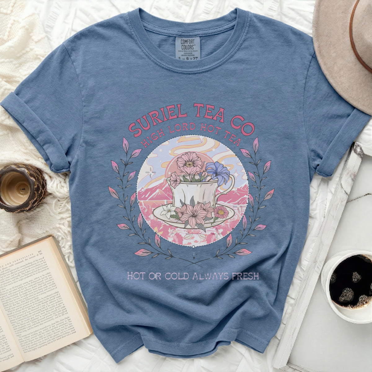 Blue t-shirt with "Suriel Tea Co" and floral teacup graphic, "Hot or Cold Always Fresh" text.