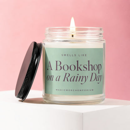Glass jar candle with lid off, lit flame, "A Bookshop on a Rainy Day" text.