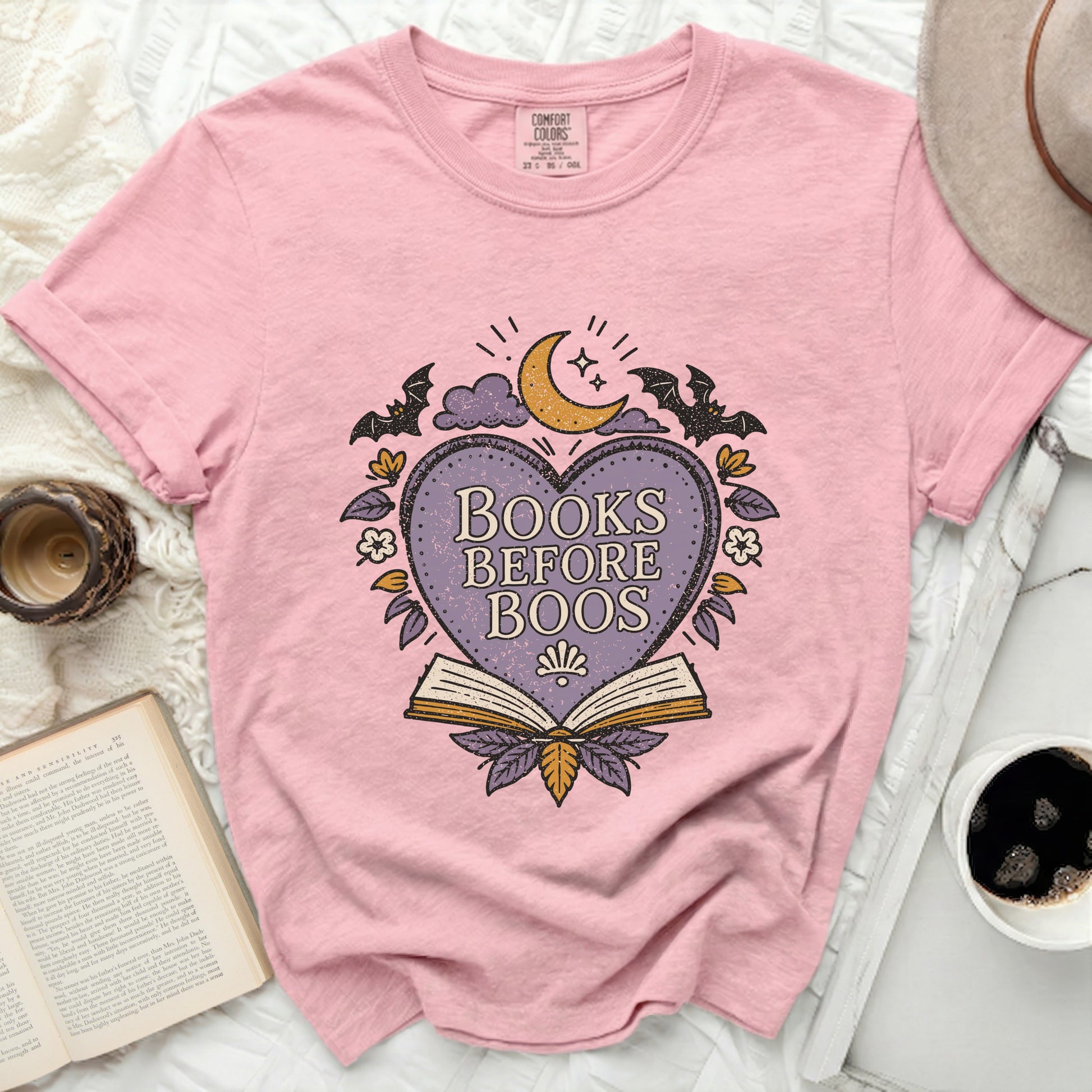 Pink t-shirt with "Books Before Boos" graphic featuring a heart, moon, bats, and open book.