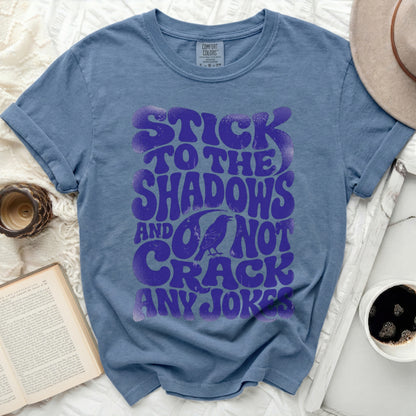 Blue t-shirt with "Stick to the shadows and not crack any jokes" text and crow graphic.