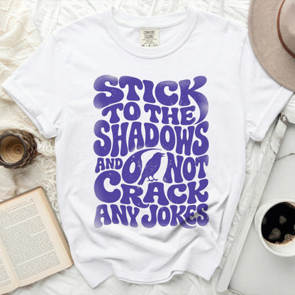 White t-shirt with purple text "Stick to the Shadows and do not crack any jokes."