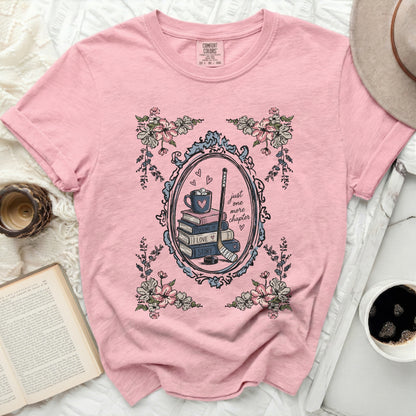 Pink t-shirt with floral frame, book stack, and hockey stick.