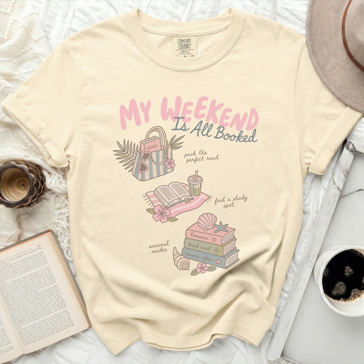Cream t-shirt with "My Weekend is All Booked" and reading-themed illustrations.