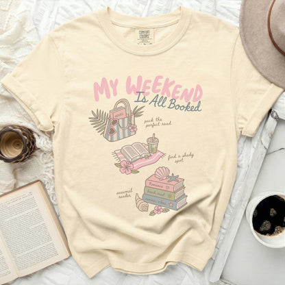 Cream t-shirt with "My Weekend is All Booked" and reading-themed illustrations.