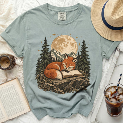 Fox reading a book under the moon and stars with mountains and trees.