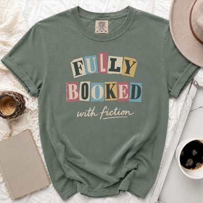 Sage green t-shirt with "Fully Booked with Fiction" text in colorful letters.
