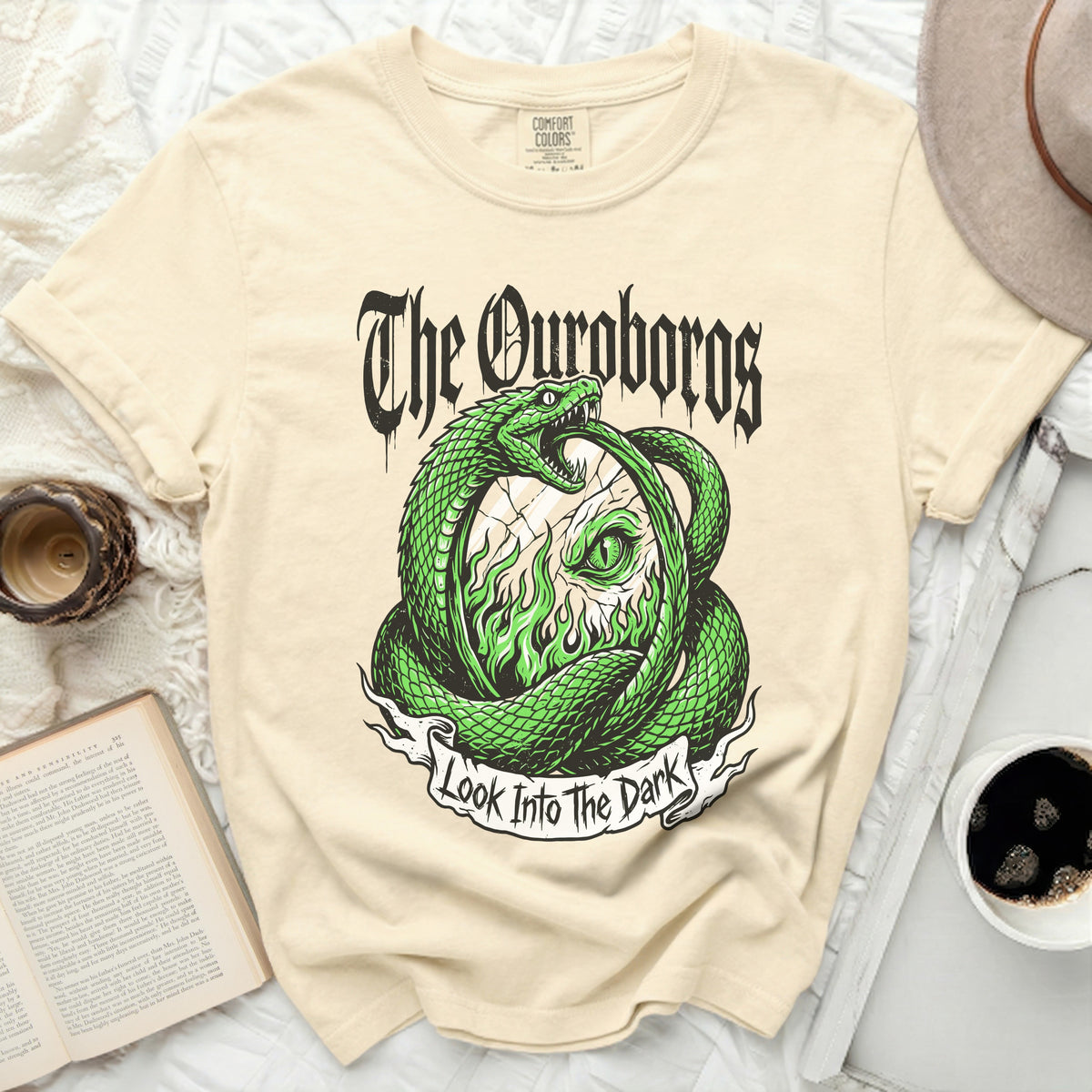 Cream t-shirt with a green Ouroboros snake design and text "The Ouroboros Look Into The Dark".