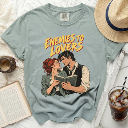 Light blue t-shirt with "Enemies to Lovers" graphic and a couple reading a book.