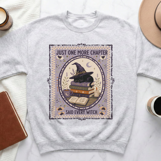 Light grey sweatshirt with a circular graphic of a black cat wearing a witch hat on books.