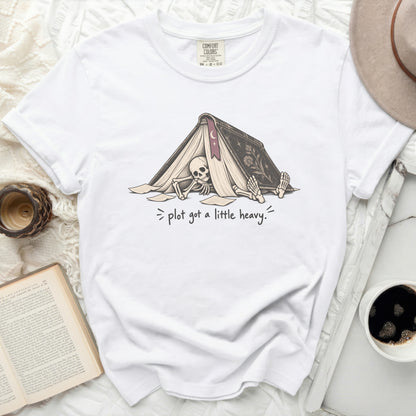 White t-shirt with graphic of skeleton under a book and text "plot got a little heavy."
