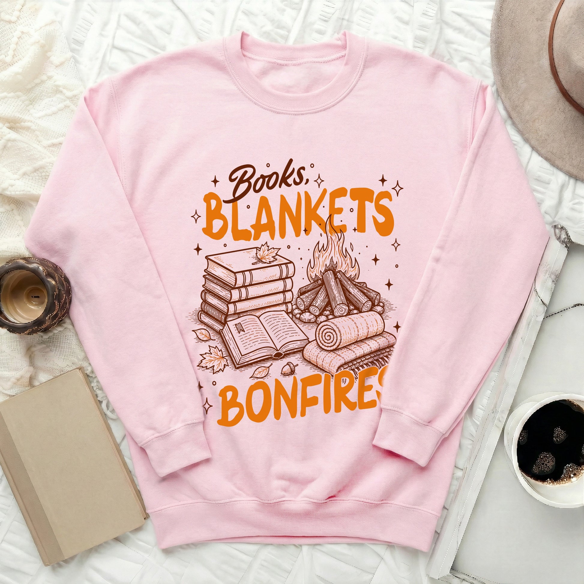 Pink sweatshirt with "Books, Blankets, Bonfires" graphic featuring books, logs, and fire.