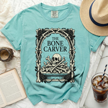 Teal t-shirt with "The Bone Carver" text and skull graphic.