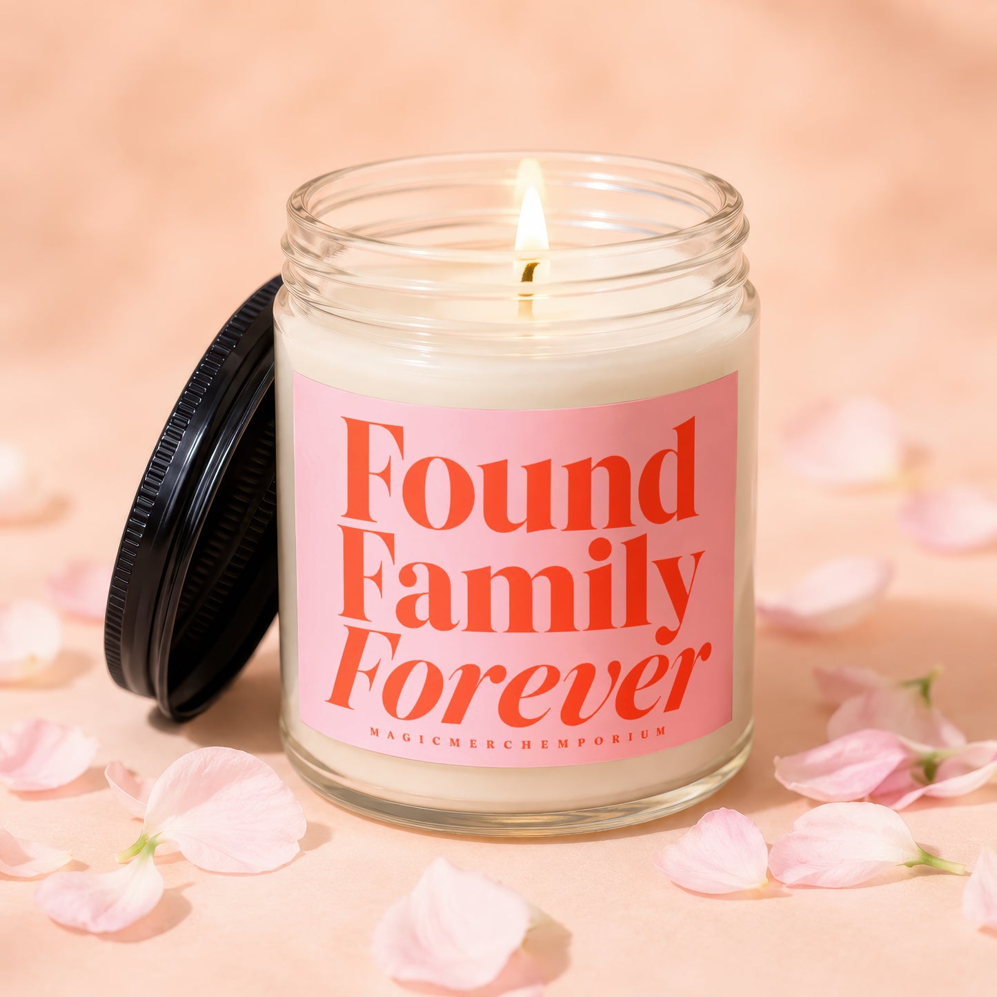 Glass candle with pink label saying "Found Family Forever" surrounded by petals.