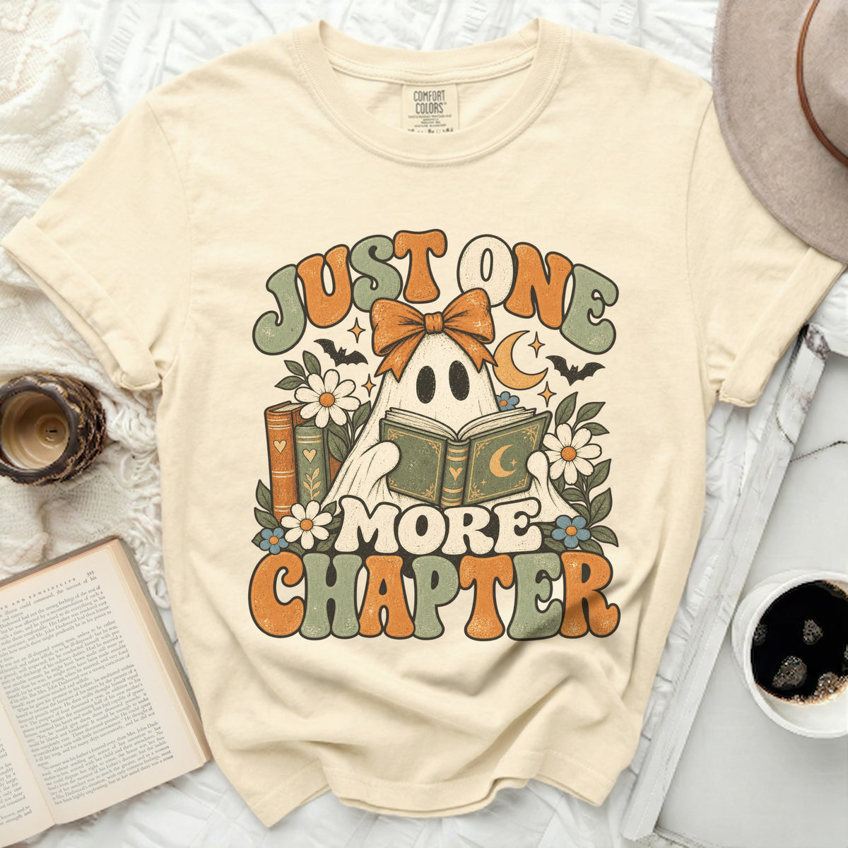Cream t-shirt with ghost reading a book and text "JUST ONE MORE CHAPTER".