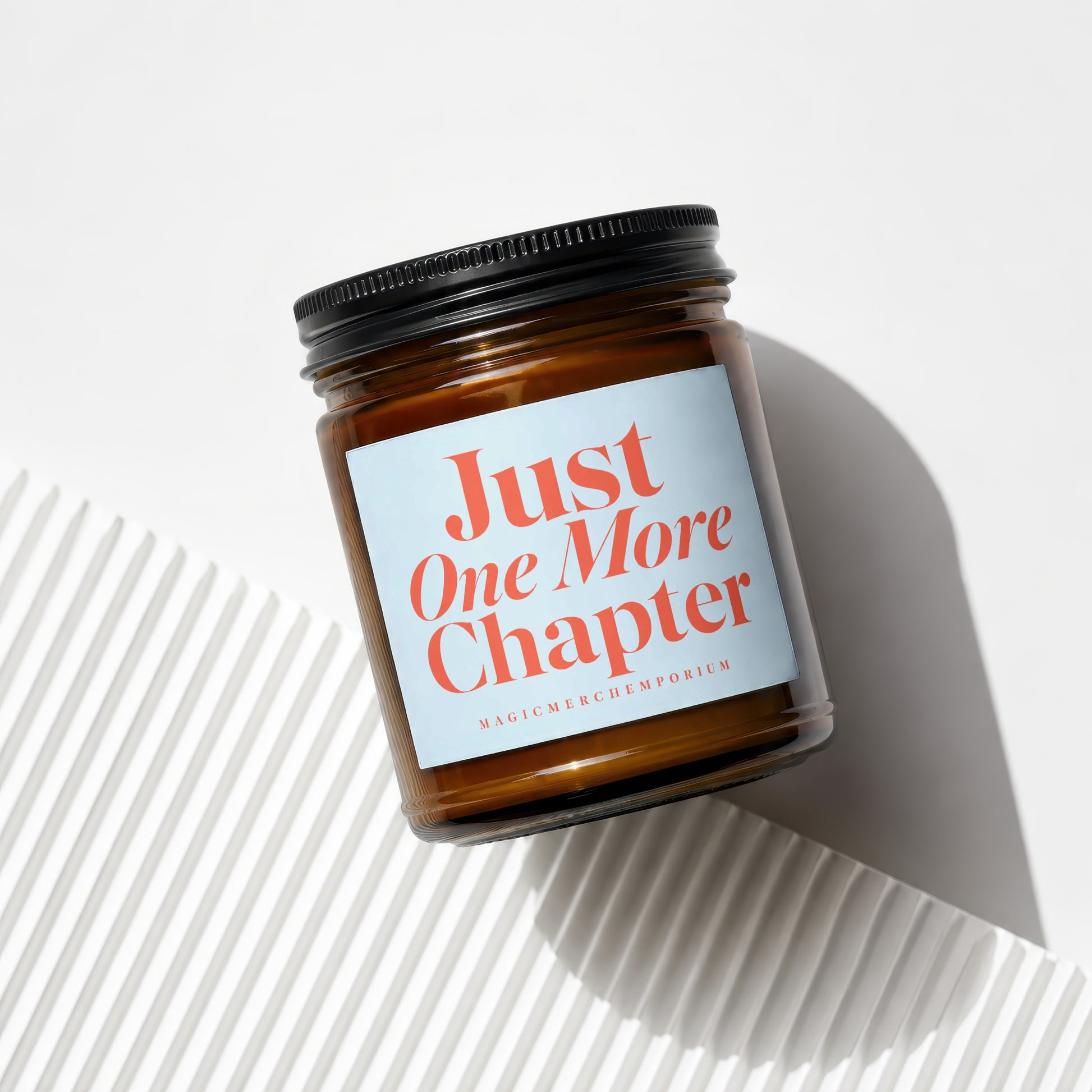 Amber jar candle with light blue label proclaiming "Just One More Chapter."
