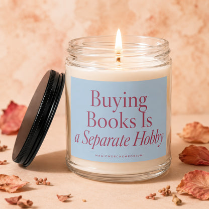 Glass candle with lit wick, reading "Buying Books Is a Separate Hobby".