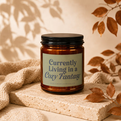 Amber jar candle with text "Currently Living in a Cozy Fantasy".