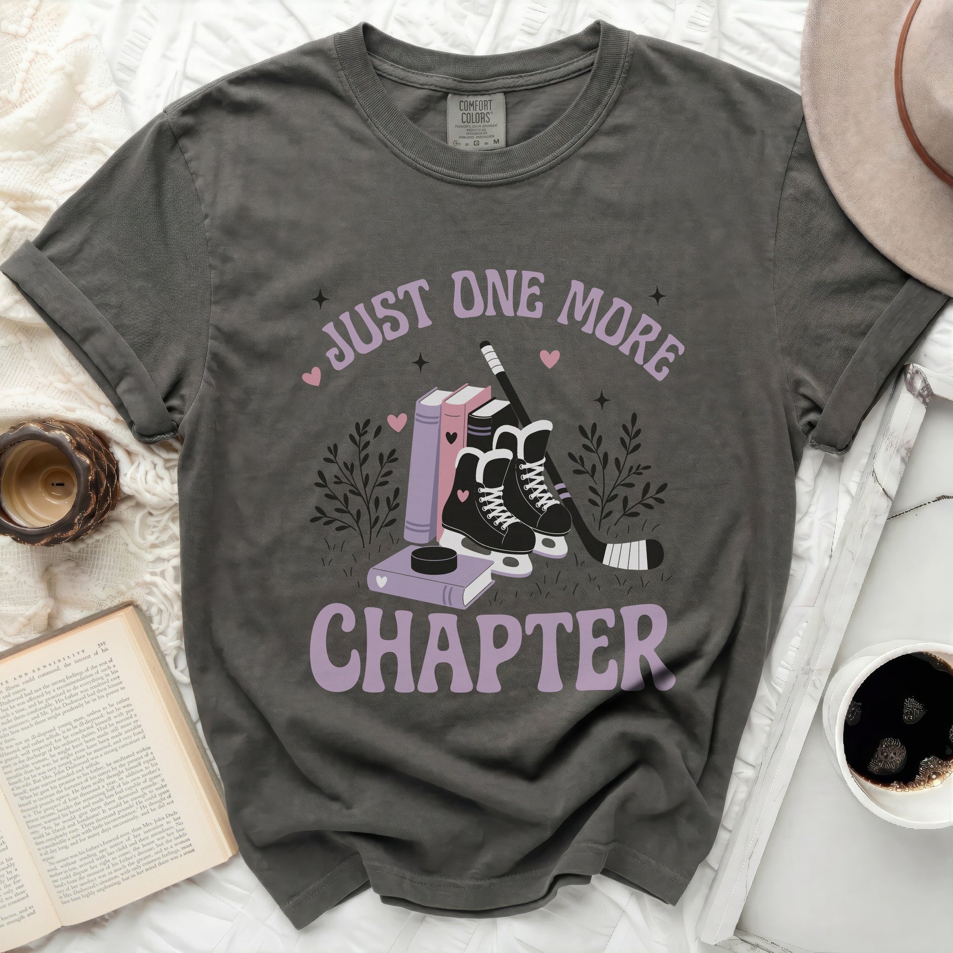 Dark t-shirt with "Just One More Chapter" text and hockey skates illustration.