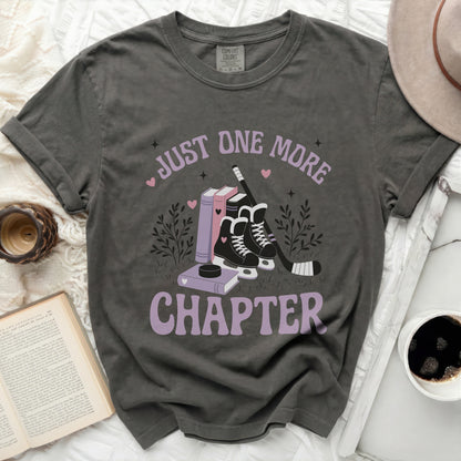Dark t-shirt with "Just One More Chapter" text and hockey skates illustration.