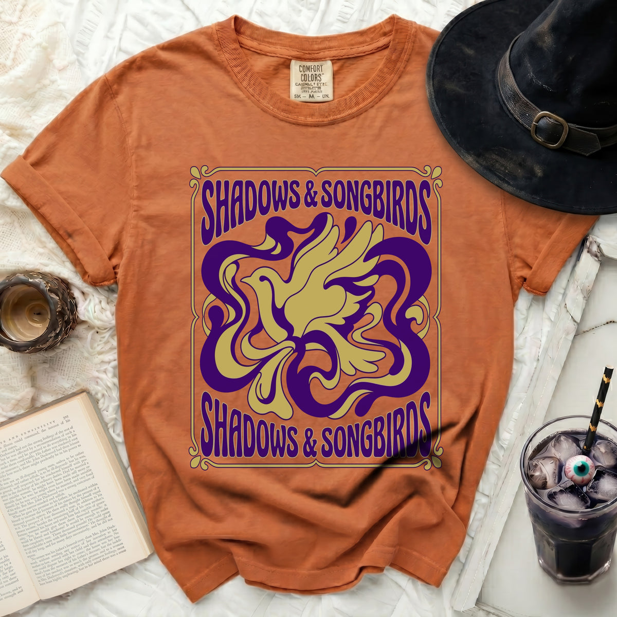 Orange t-shirt with "Shadows & Songbirds" text and a stylized bird design.