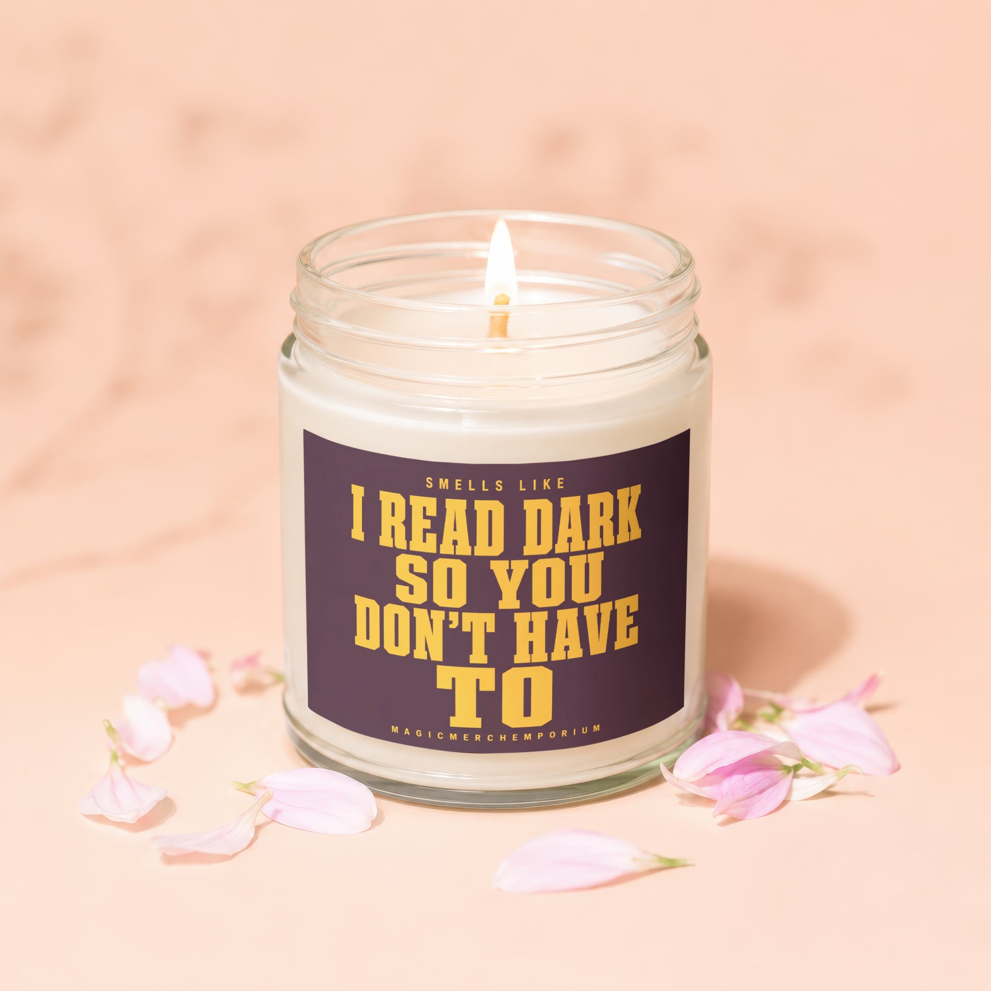 Lit candle in glass jar with purple label reading "Smells Like I Read Dark So You Don't Have To."