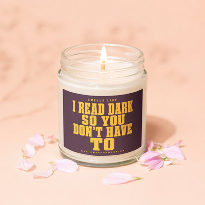 Lit candle in glass jar with purple label reading "Smells Like I Read Dark So You Don't Have To."