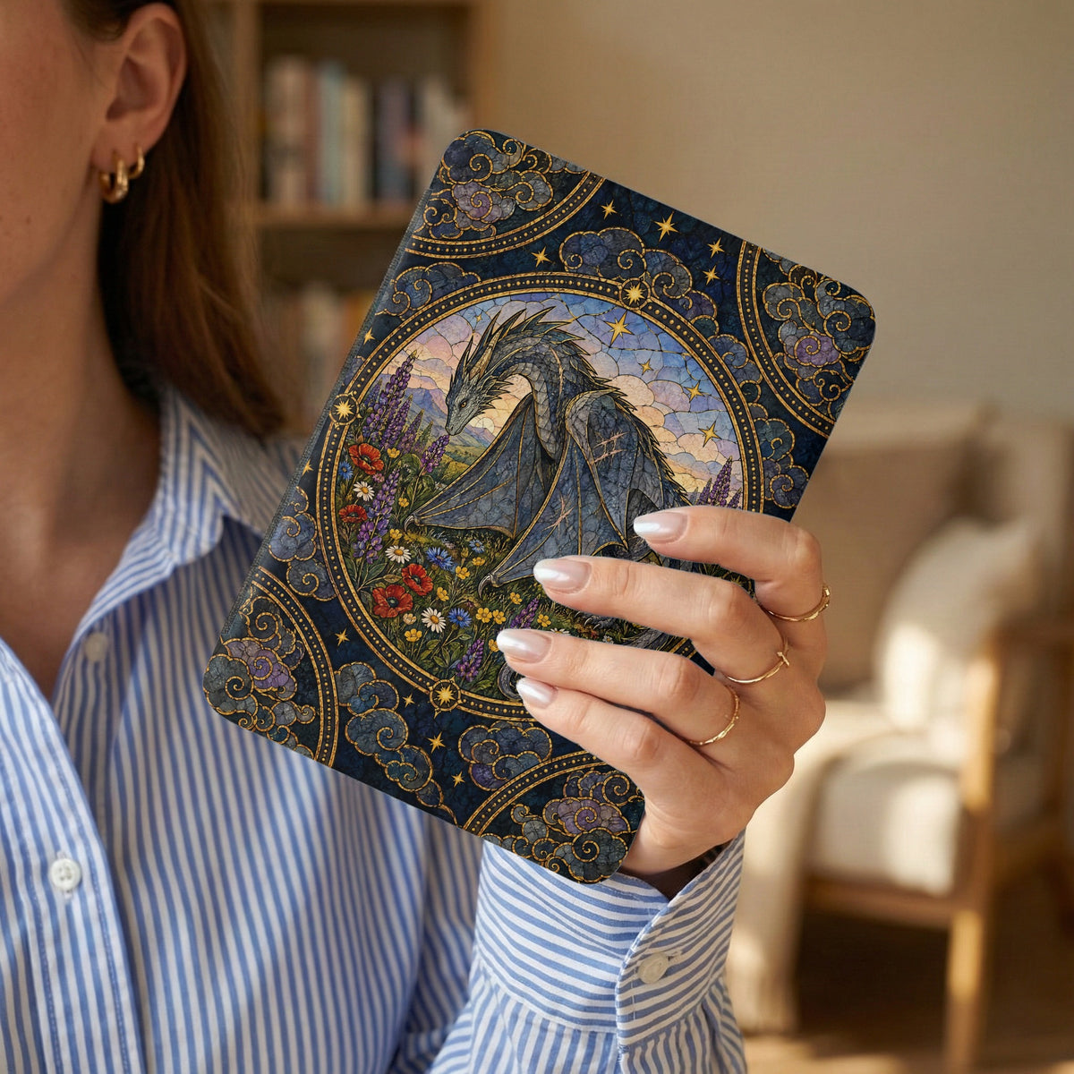 A person holds a blue e-reader case featuring a mosaic-style dragon and floral design in gold and blue tones.