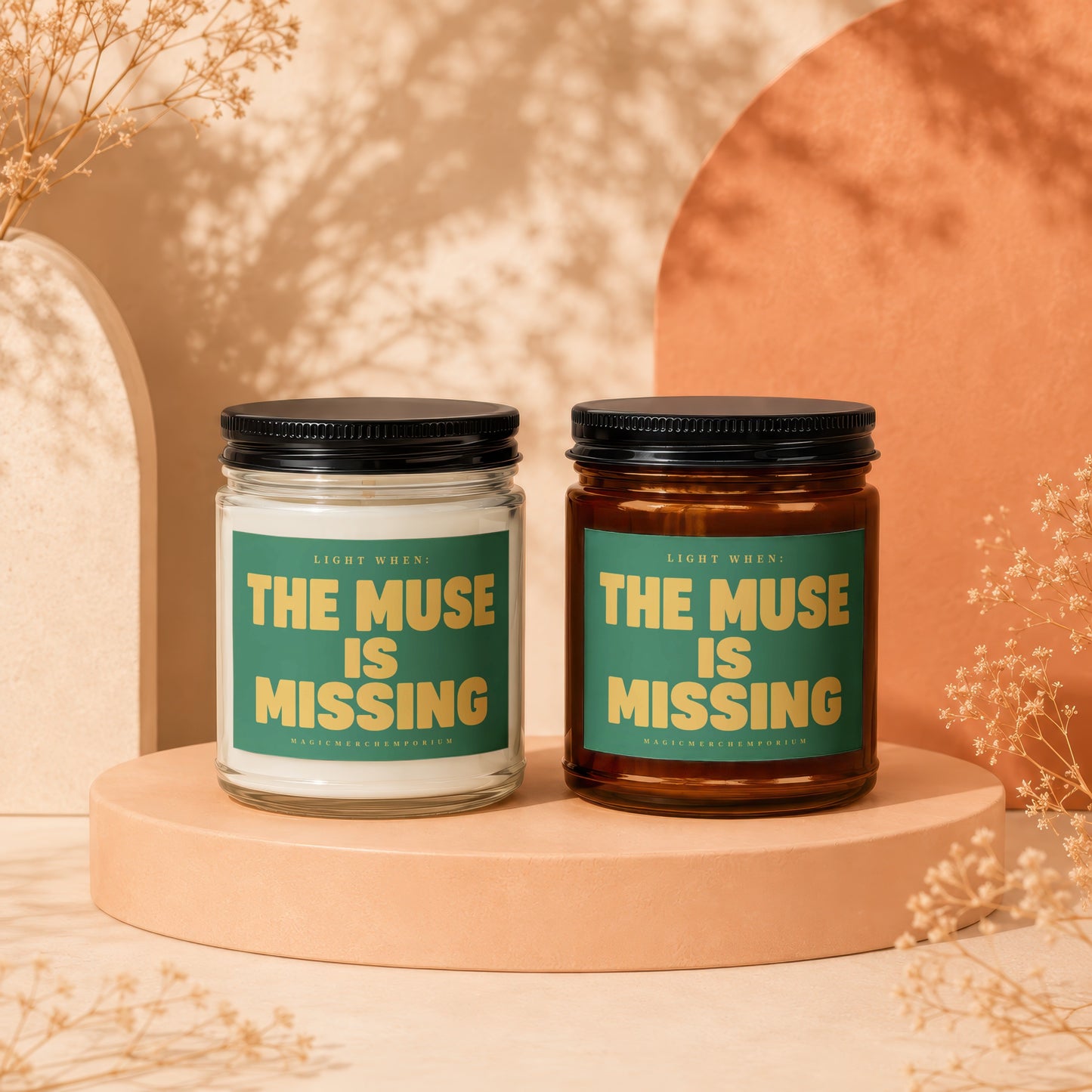 Two candles, one white and one amber, with green labels saying "The Muse Is Missing."