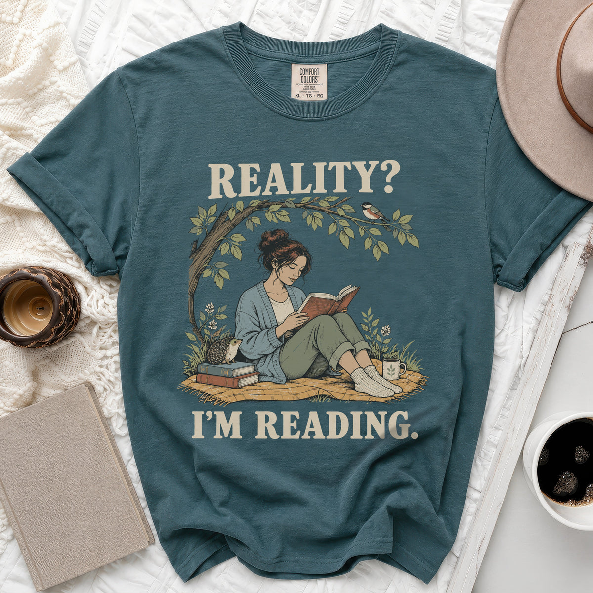 Teal Comfort Colors t-shirt with "REALITY? I'M READING." text and illustration.