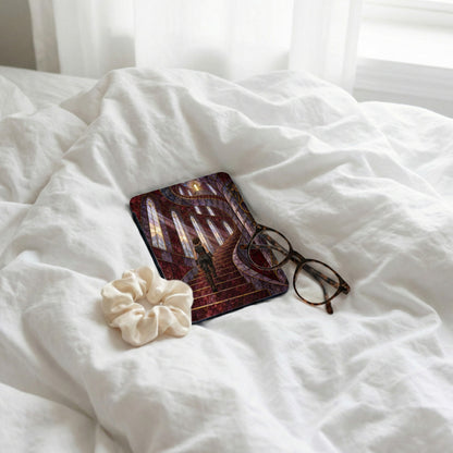 E-reader with stained glass staircase design, scrunchie, and glasses on white bedding.