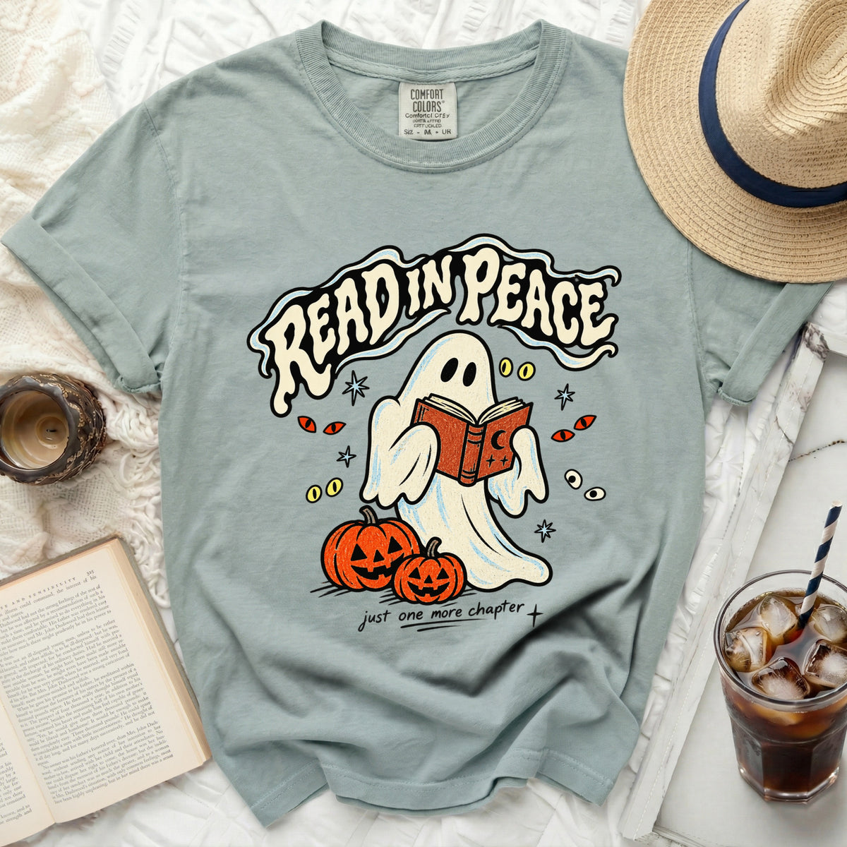 Ghost reading a book with pumpkins on a t-shirt that says "Read In Peace."