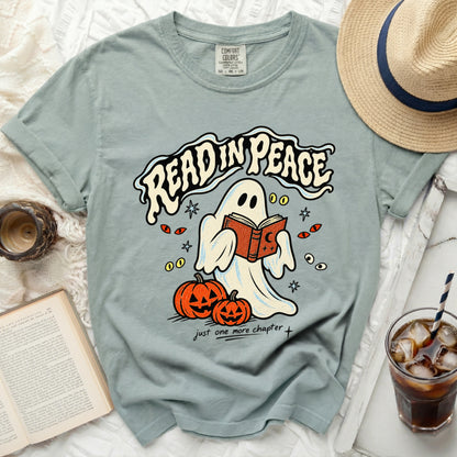 Ghost reading a book with pumpkins on a t-shirt that says "Read In Peace."