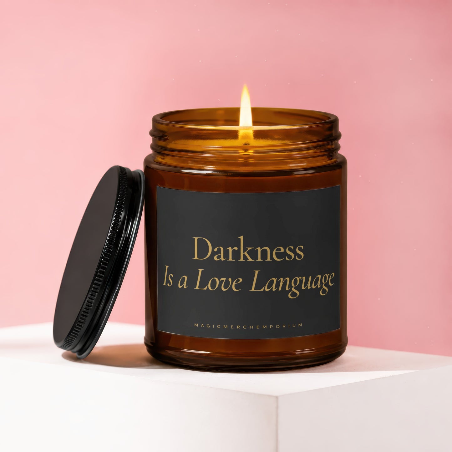 Amber jar candle with lit flame, black lid to the side, reads "Darkness Is a Love Language".