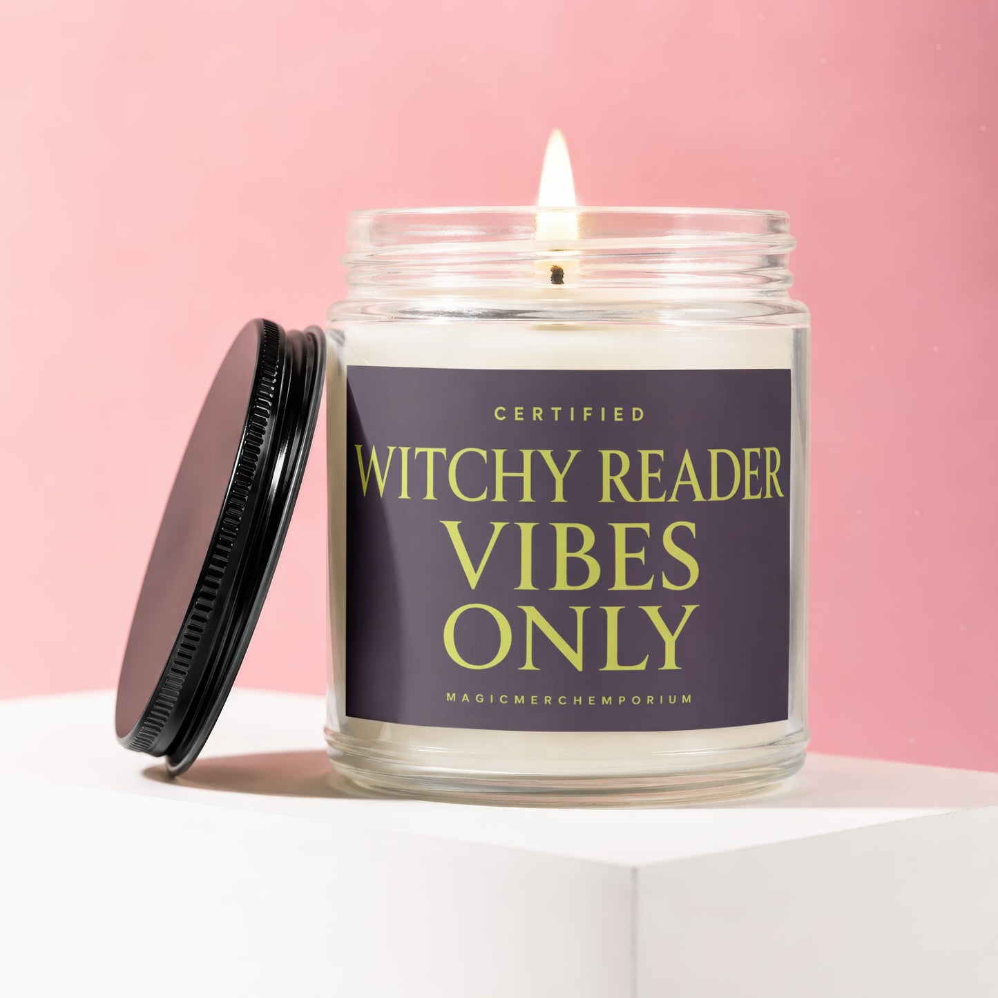 Glass candle with a lit wick and a dark label reading "WITCHY READER VIBES ONLY"