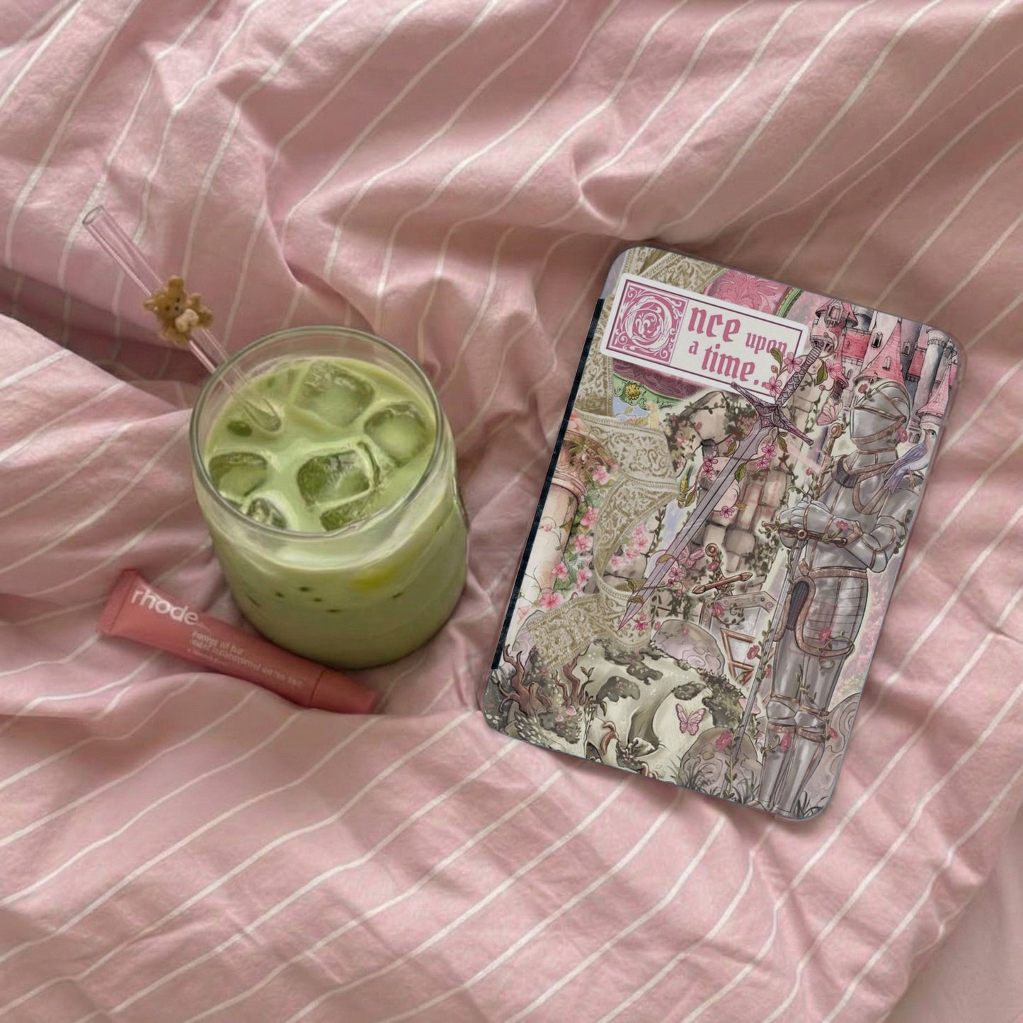 Green iced beverage, pink lip balm, and fairytale journal with text "once upon a time".