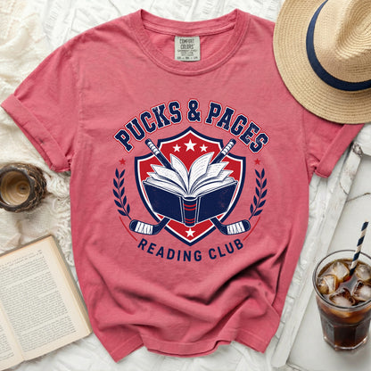 T-shirt with "Pucks & Pages Reading Club" logo and hockey sticks.