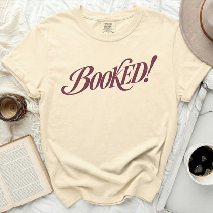 Cream t-shirt with burgundy text that reads "Booked!".