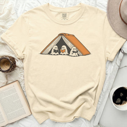 Three ghosts reading books inside an open book graphic on a beige t-shirt.
