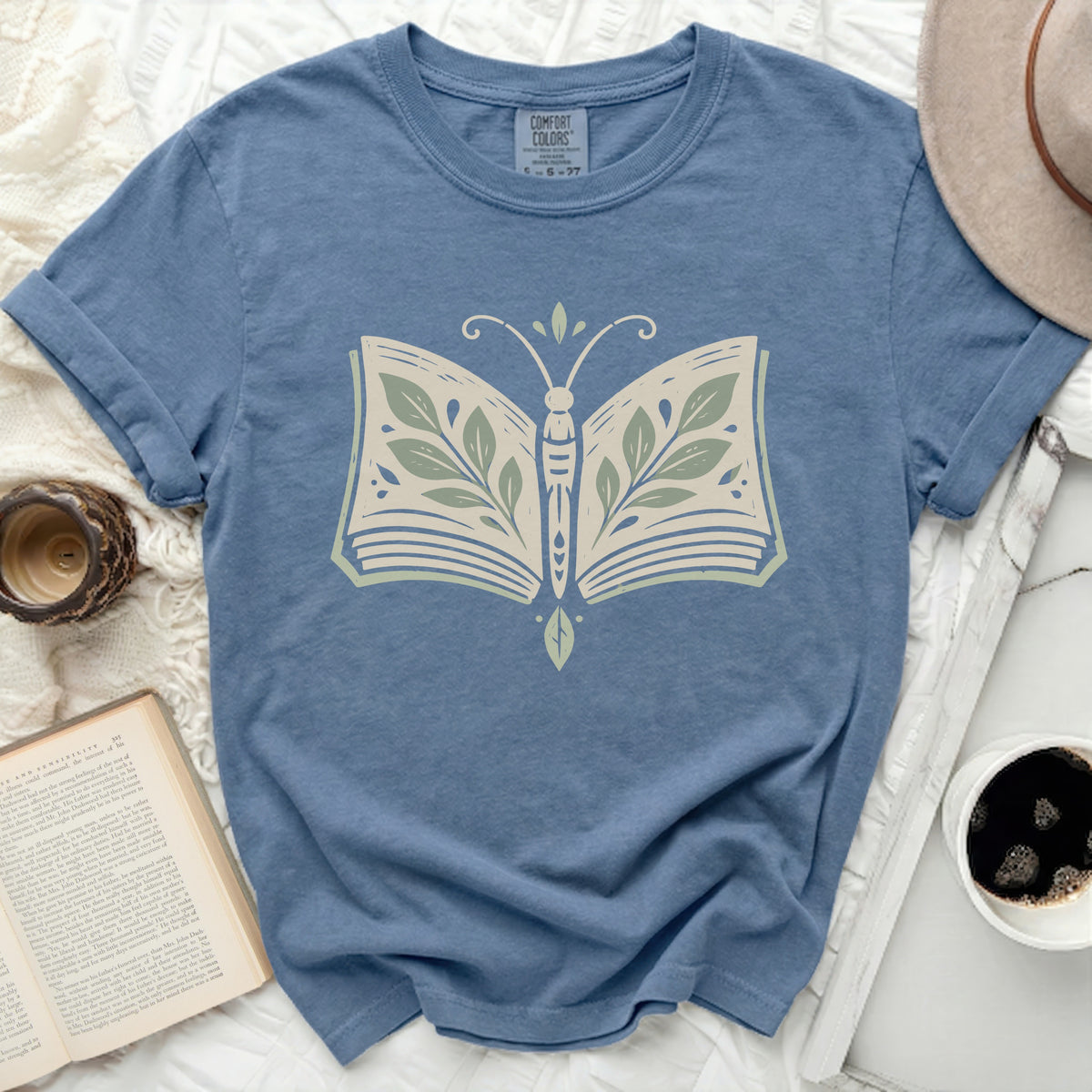 Blue t-shirt with a butterfly design made of an open book and leaves.