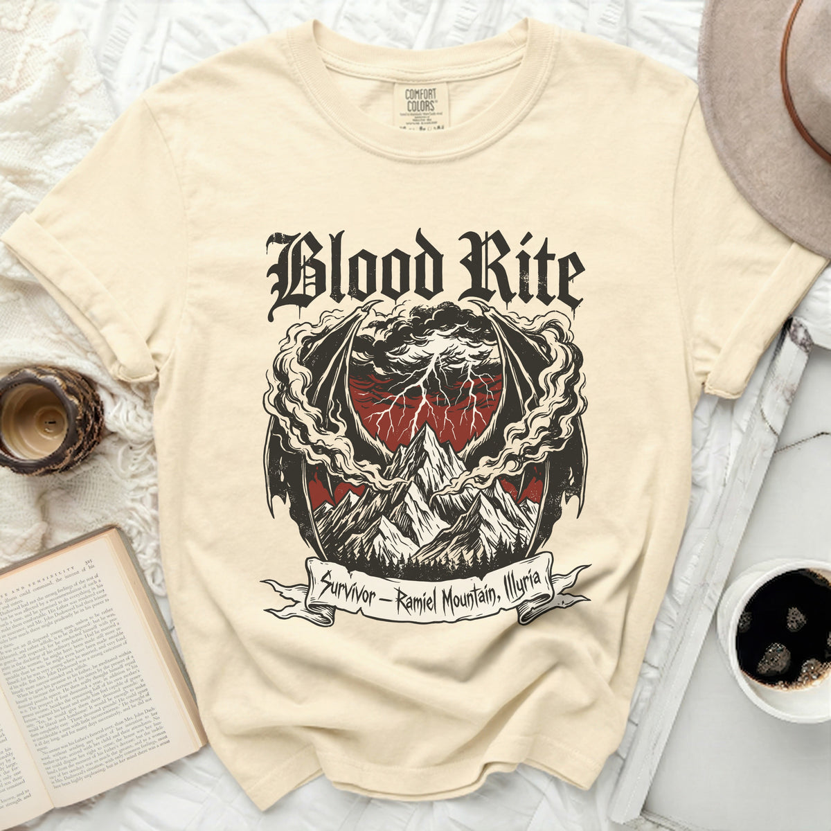 Cream t-shirt with "Blood Rite" graphic of mountains, storm, and dragon wings.