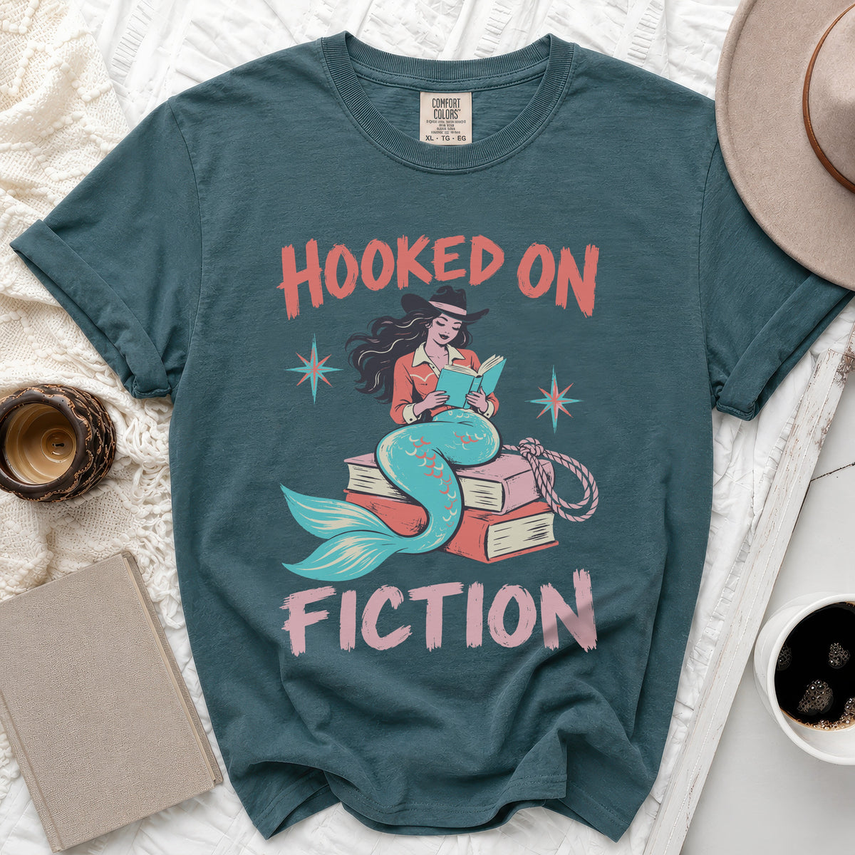 Teal t-shirt with "Hooked on Fiction" text and mermaid reading a book.