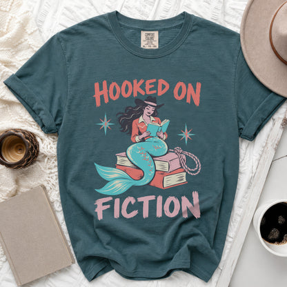 Teal t-shirt with "Hooked on Fiction" text and mermaid reading a book.
