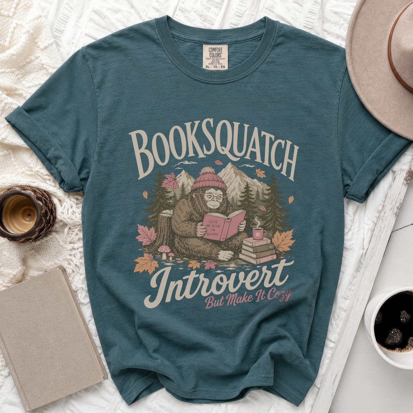 Teal t-shirt with Bigfoot reading, "Booksquatch Introvert But Make It Cozy" text.
