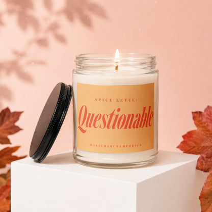 Glass candle labeled "Spice Level: Questionable" with a lit wick.