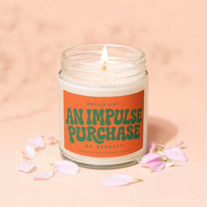 Candle with orange label reading "Smells like an impulse purchase. No regrets. MagicMerchEmporium."
