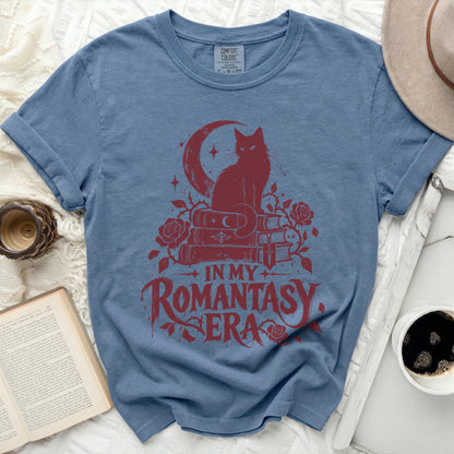 Blue t-shirt with red graphic of cat on books, moon, roses, and text "IN MY ROMANTASY ERA".