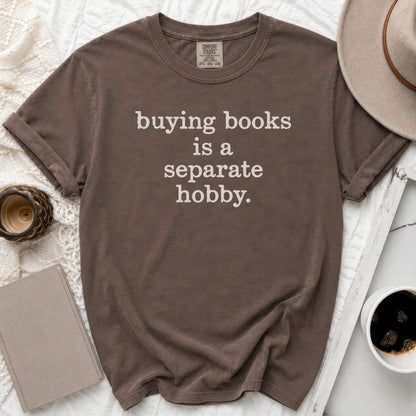 Brown t-shirt with white text reading "buying books is a separate hobby."